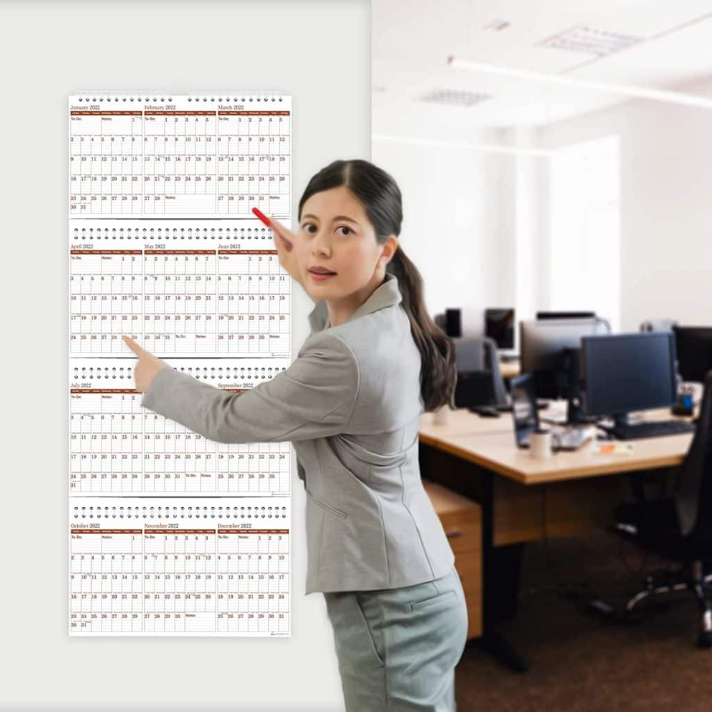 woman pointing at the yearly hanging wall calendar